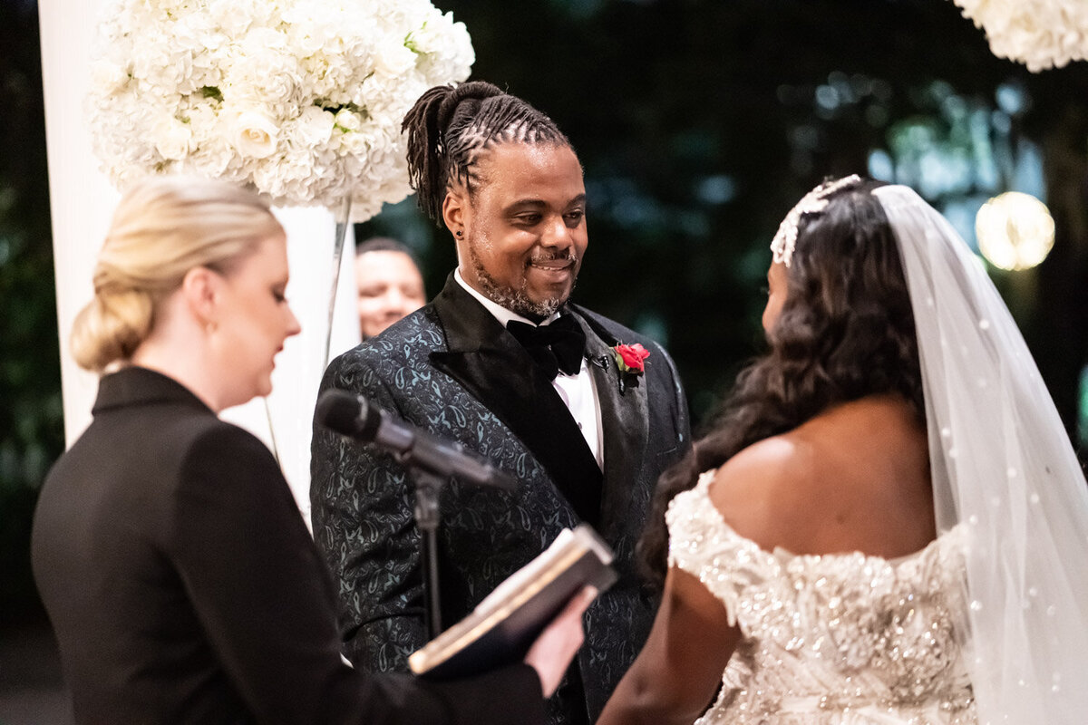 Groom smiles at bride during ceremony