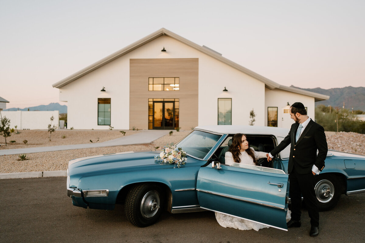 bride and groom with vintage car in front of venue