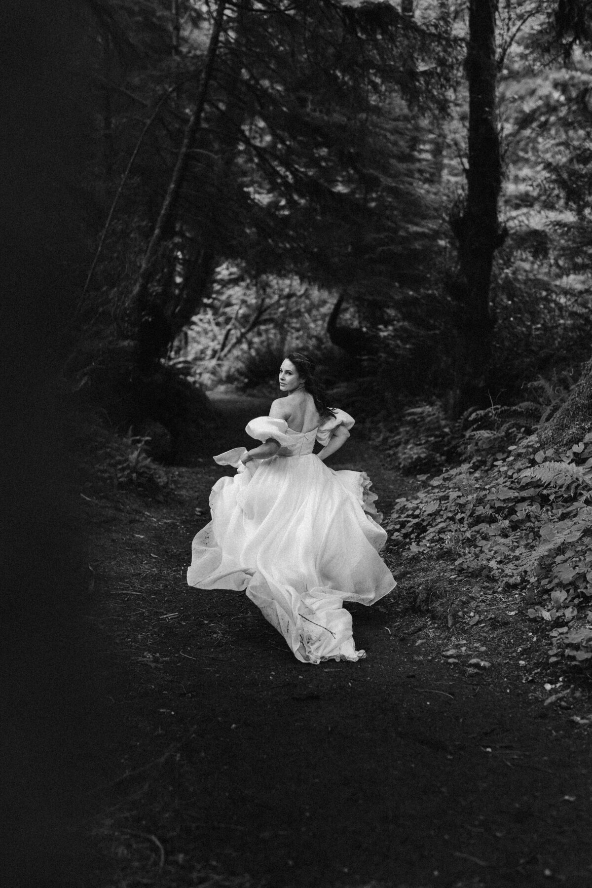 Bride in a chiffon gown by Leanne Marshall gown, running through a forest in Oregon Coast