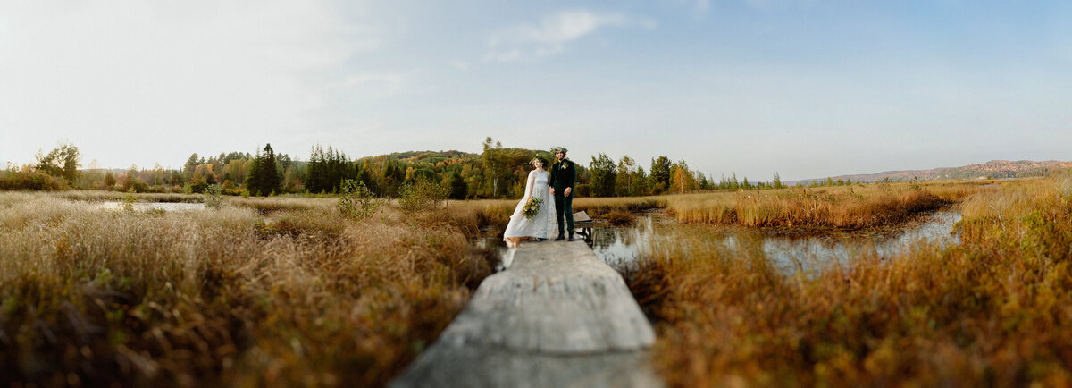 bride-and-groom-on-a-boardwalk-posing-surounded-with-fall-colors