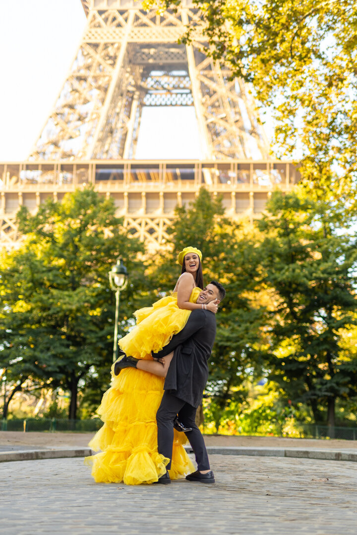 Paris street couple photoshoot, yellow dress with matching beret, lift pose, Eiffel Tower view, romantic photography