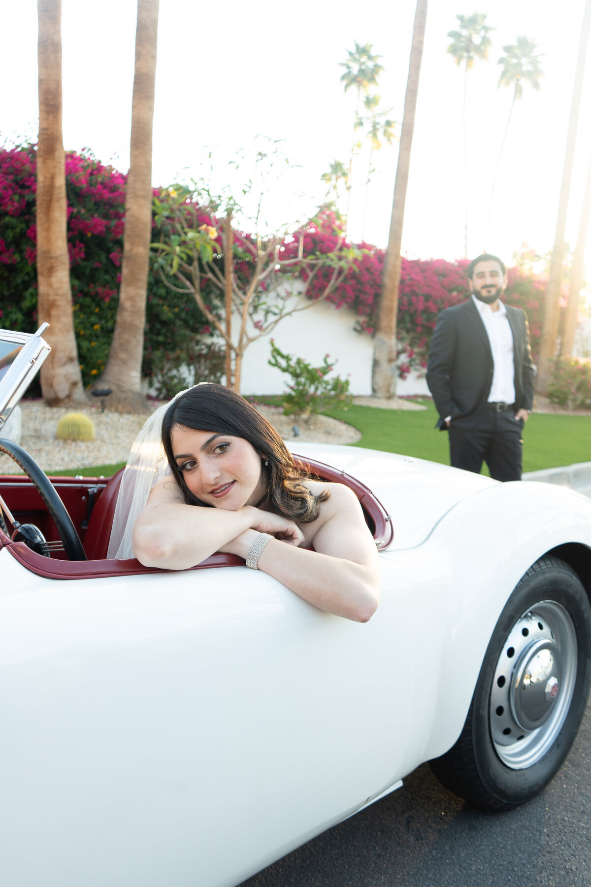 Bride and groom in a vintage car in Palm Springs during dawn with the groom looking lovingly at the bride 