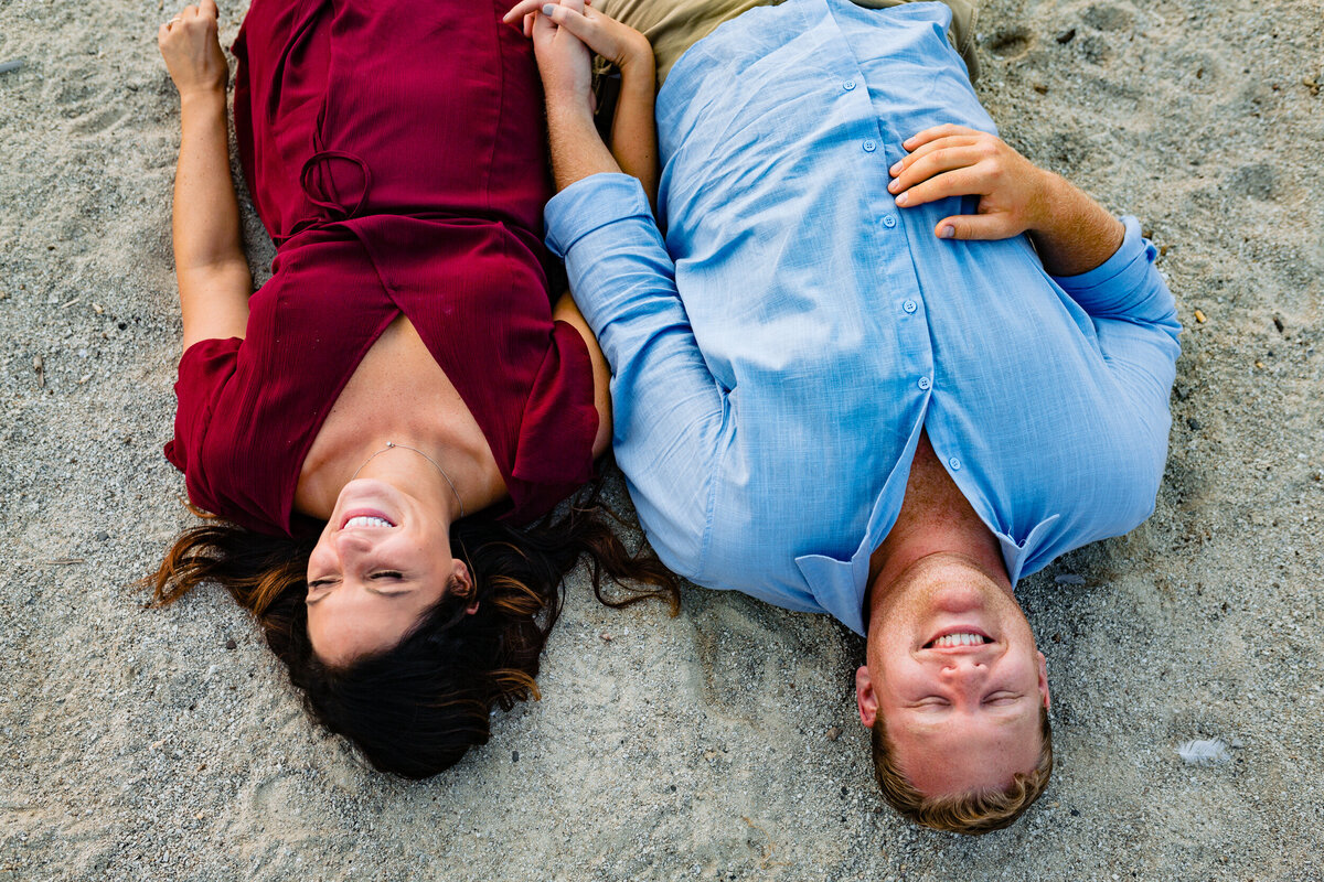 A couple lays on the beach during their engagement photos at Maumee Bay.  Photo By Adore Wedding Photography. Toledo Wedding Photographers