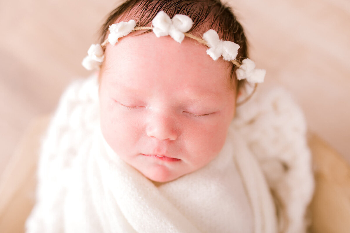Close up of a babys face with white bows on her head