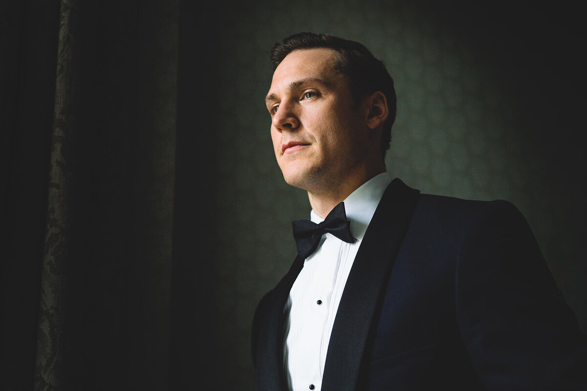 A stylish grooms wedding portrait of the green looking out of the window