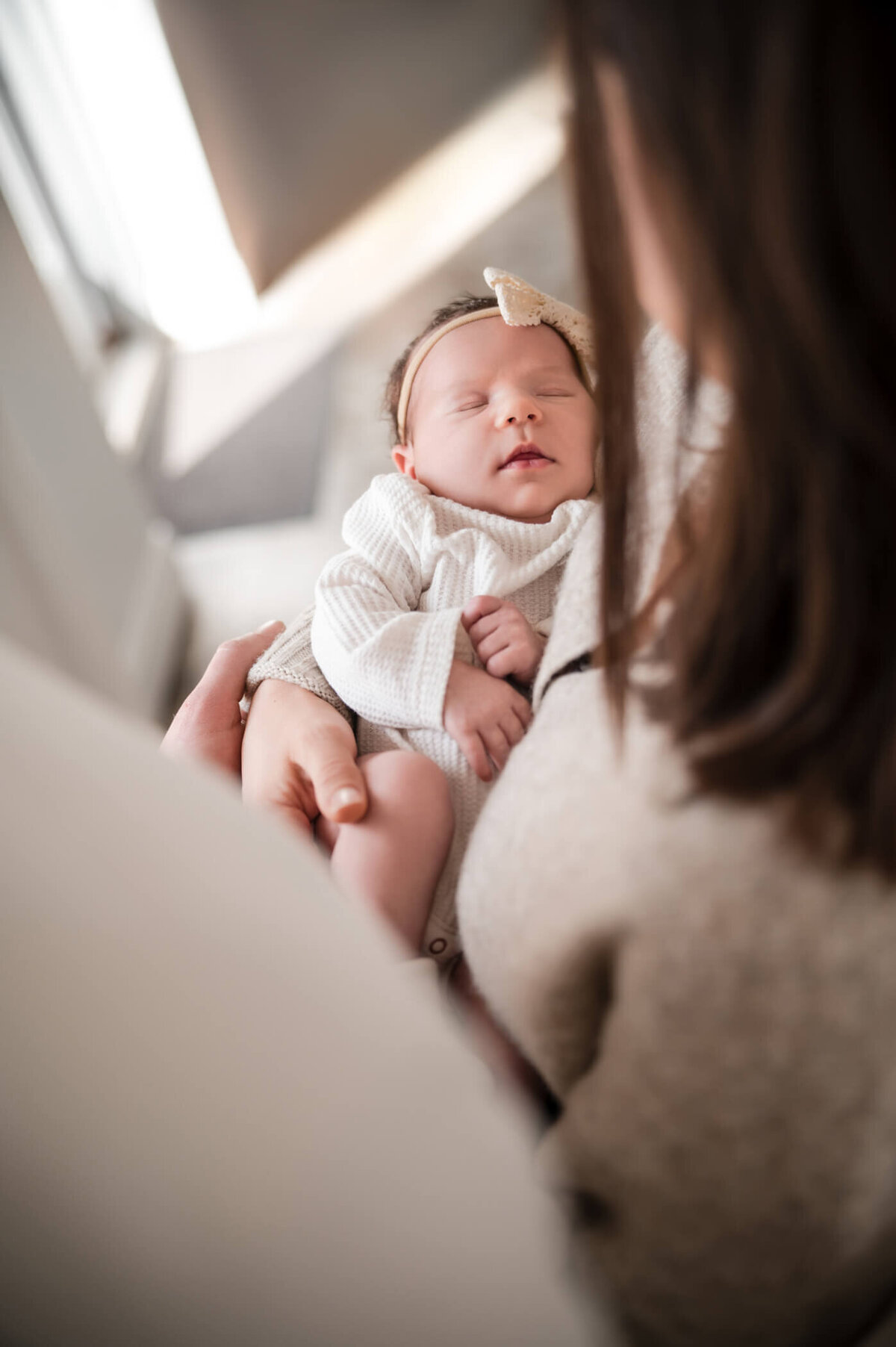 looking down at a sleeping newborn in mom's arms