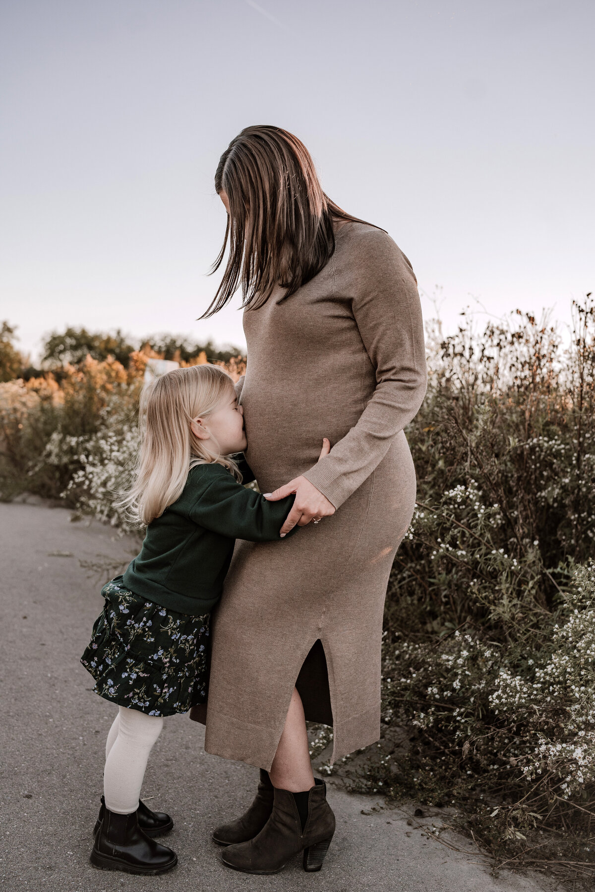 child kissing moms ababy bump