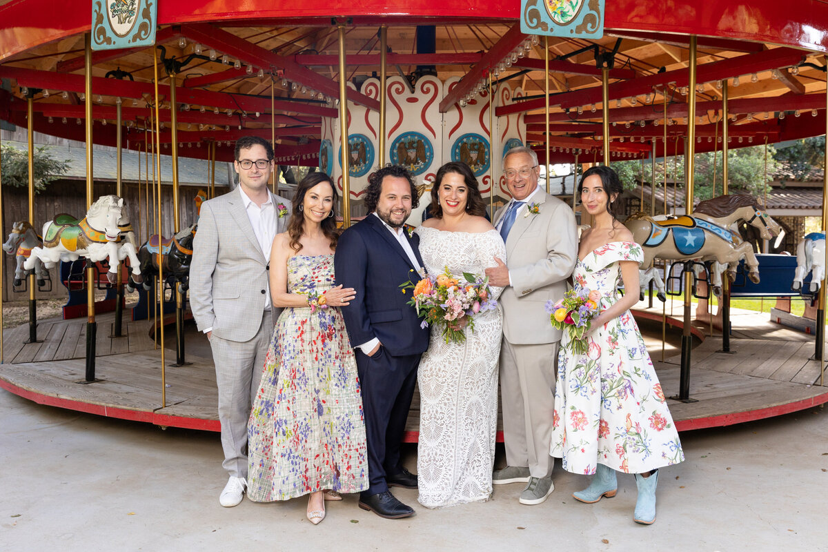 A newlywed couple with their family standing around them