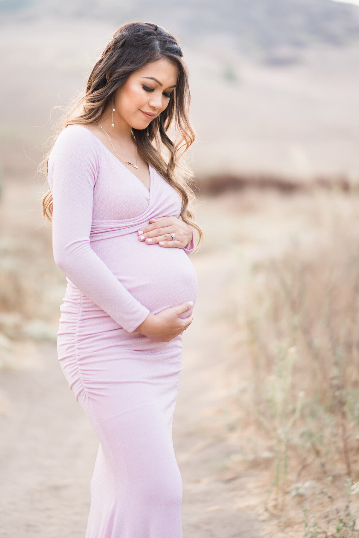 Pregnant mom holding belly in pink bodycon dress from PinkBlush Maternity
