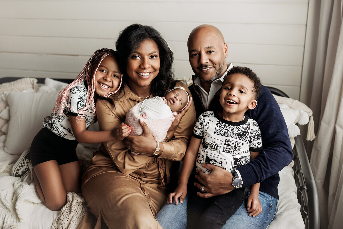 Fort Collins family posing with their new baby sister by a big window