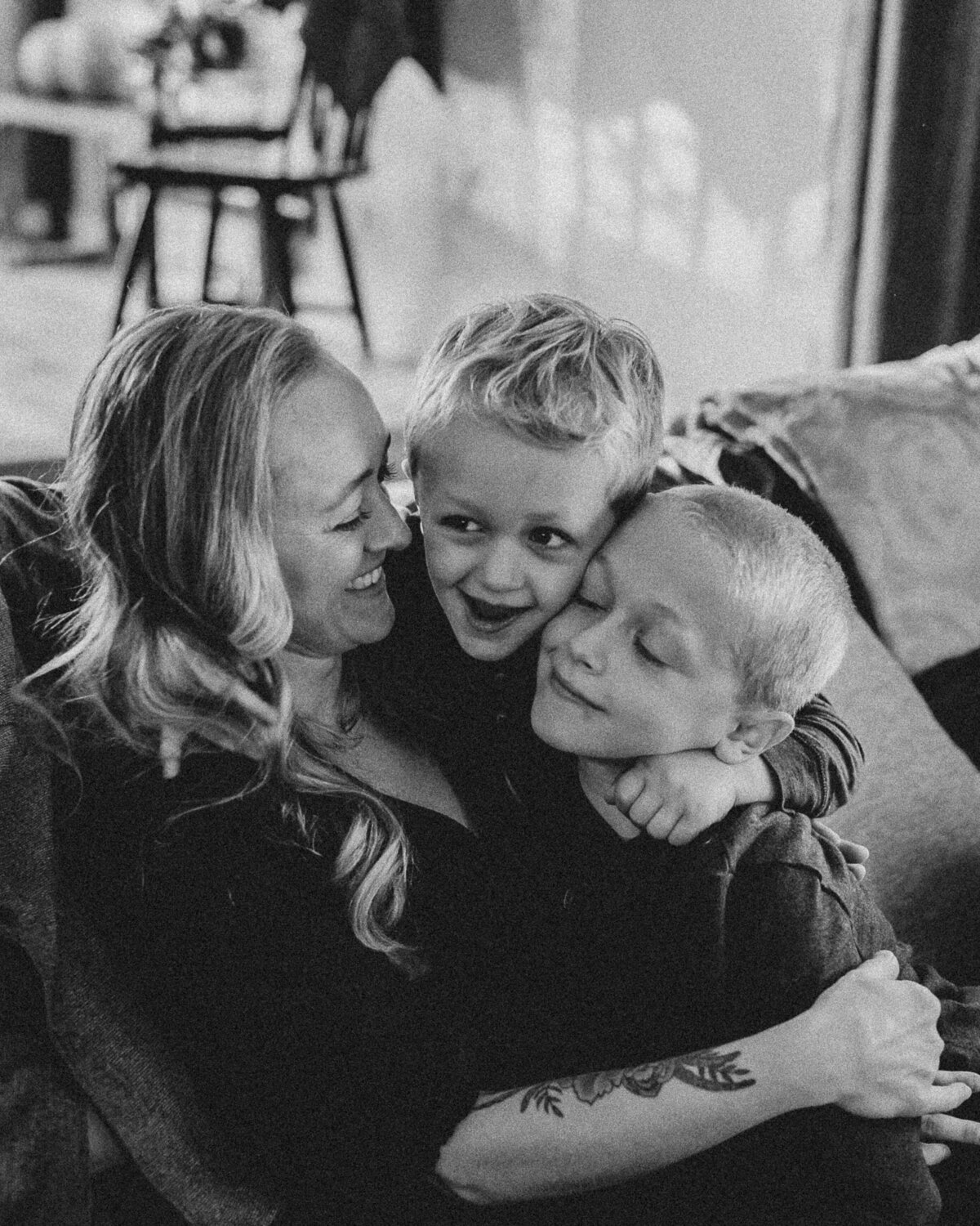 A candid black and white image of a mother, laughing with two of her sons in their home in Denver Colorado.