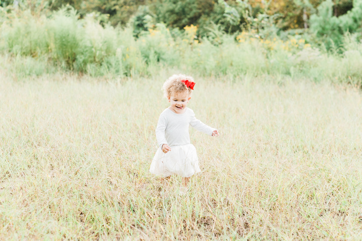 Toddler dances in a field during a Raleigh family photo session. Photographed by Raleigh family photographer A.J. Dunlap Photography.