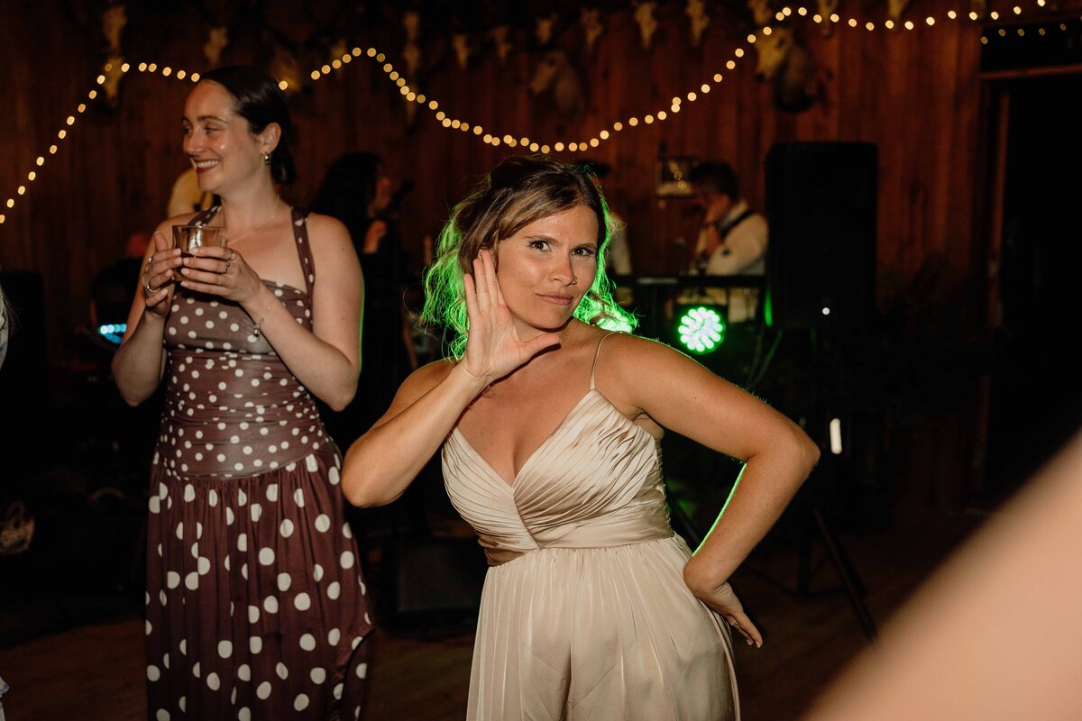 A flash photograph of a wedding guest striking a pose on the dance floor. 
