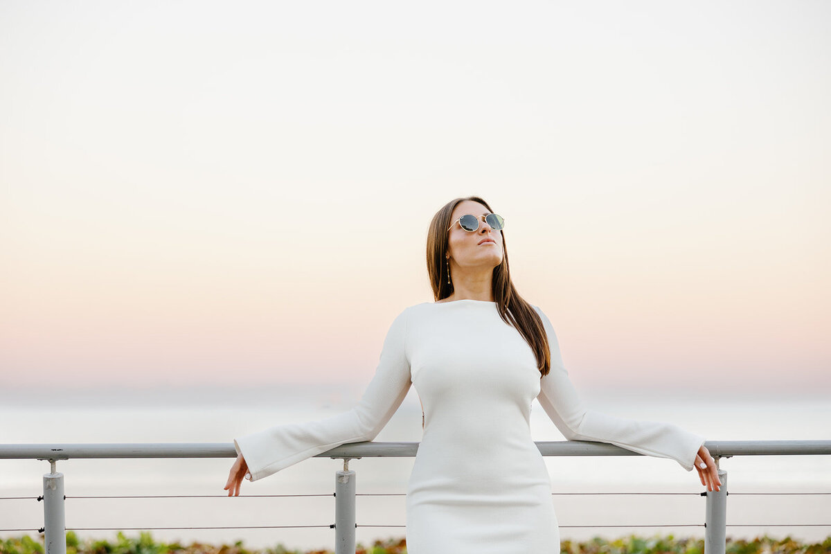 Rebecca stands with her arms wide open, feeling the warmth of the sunset on her face during her breathtaking Florida engagement session at Marriott Hotel Fort Lauderdale.