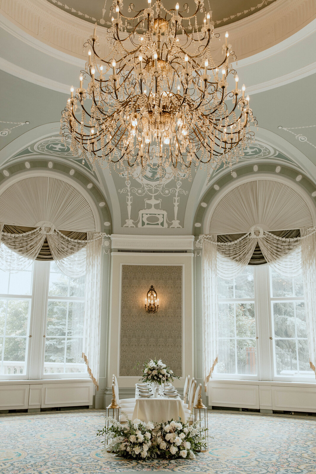 Timeless and elegant reception decor set up with stunning white florals large chandelier in the ballroom at Fairmont Hotel, classic and experienced, Edmonton wedding venue, featured on the Brontë Bride Vendor Guide.