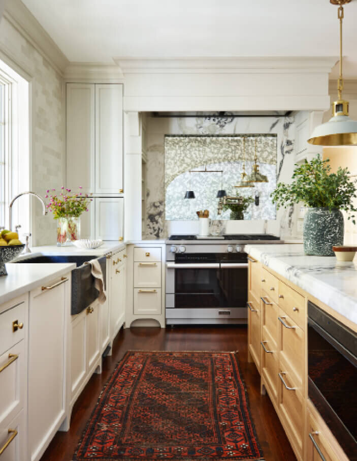 Milton kitchen designer created custom white cabinets with a natural oak island, vintage area rug, Miele appliances, a custom hood, artisan tile, and marble counters.