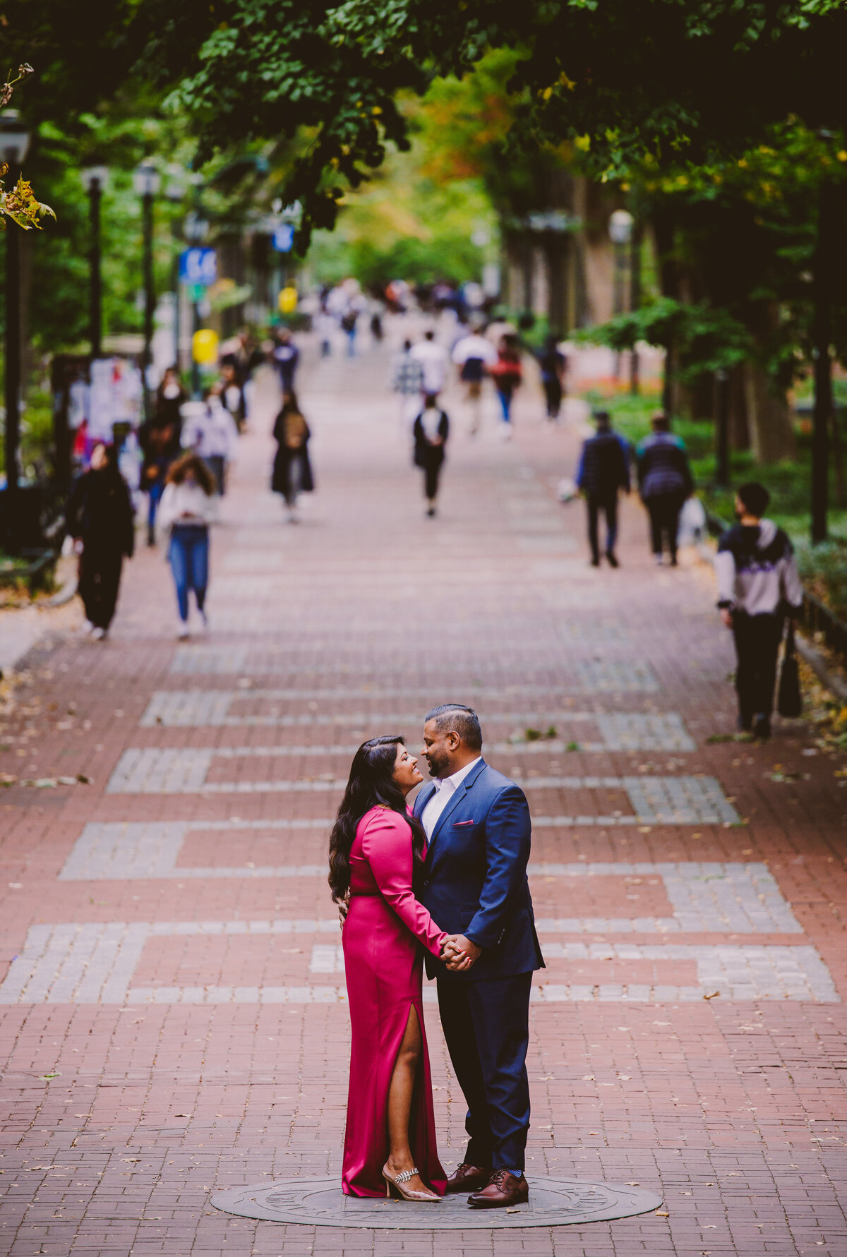 A couple standing on a brick path inside the upenn campus at university of pennsylvania during their engagement session