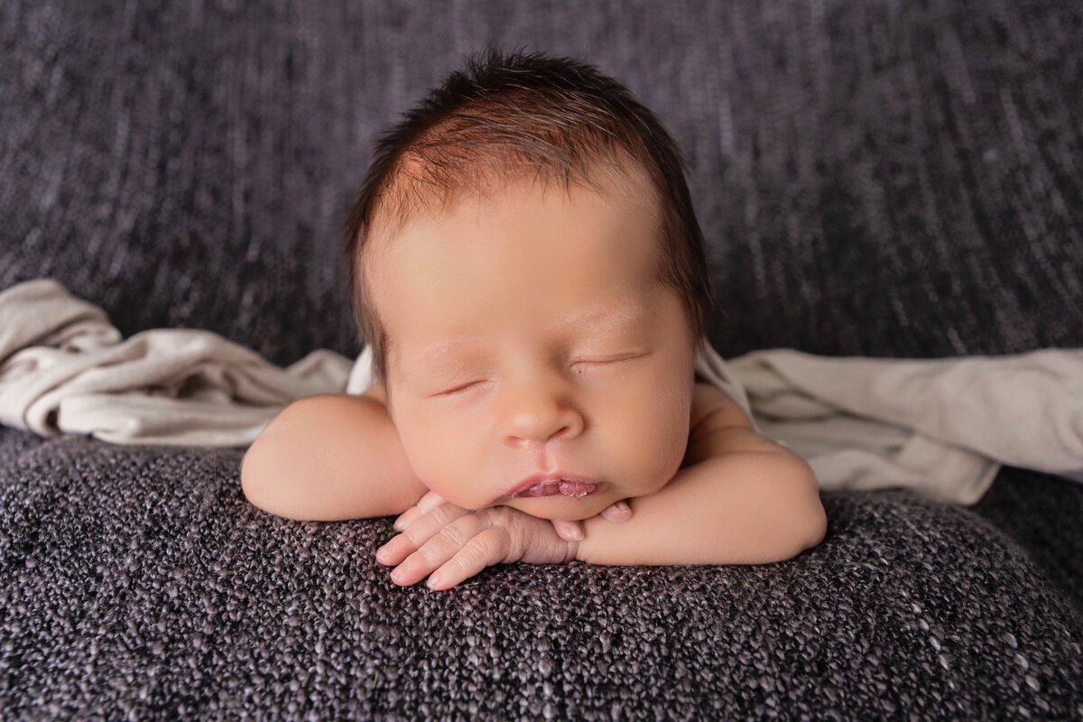 sleeping newborn on dark grey blanket on tummy