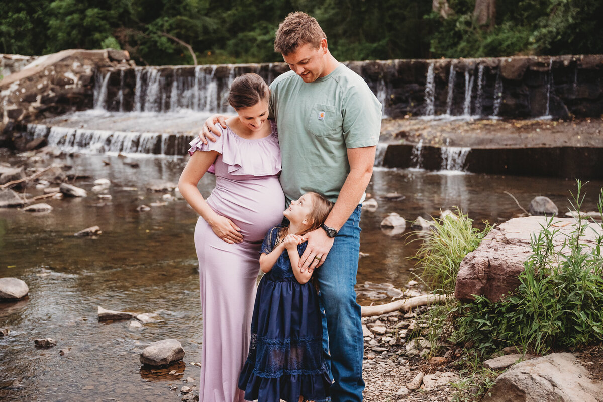 Family outside near waterfall with pregnant mom