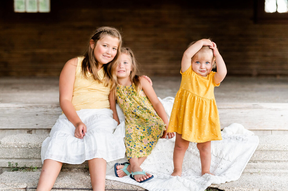 Three sister sitting on outdoor steps at family session in Geneva, IL.