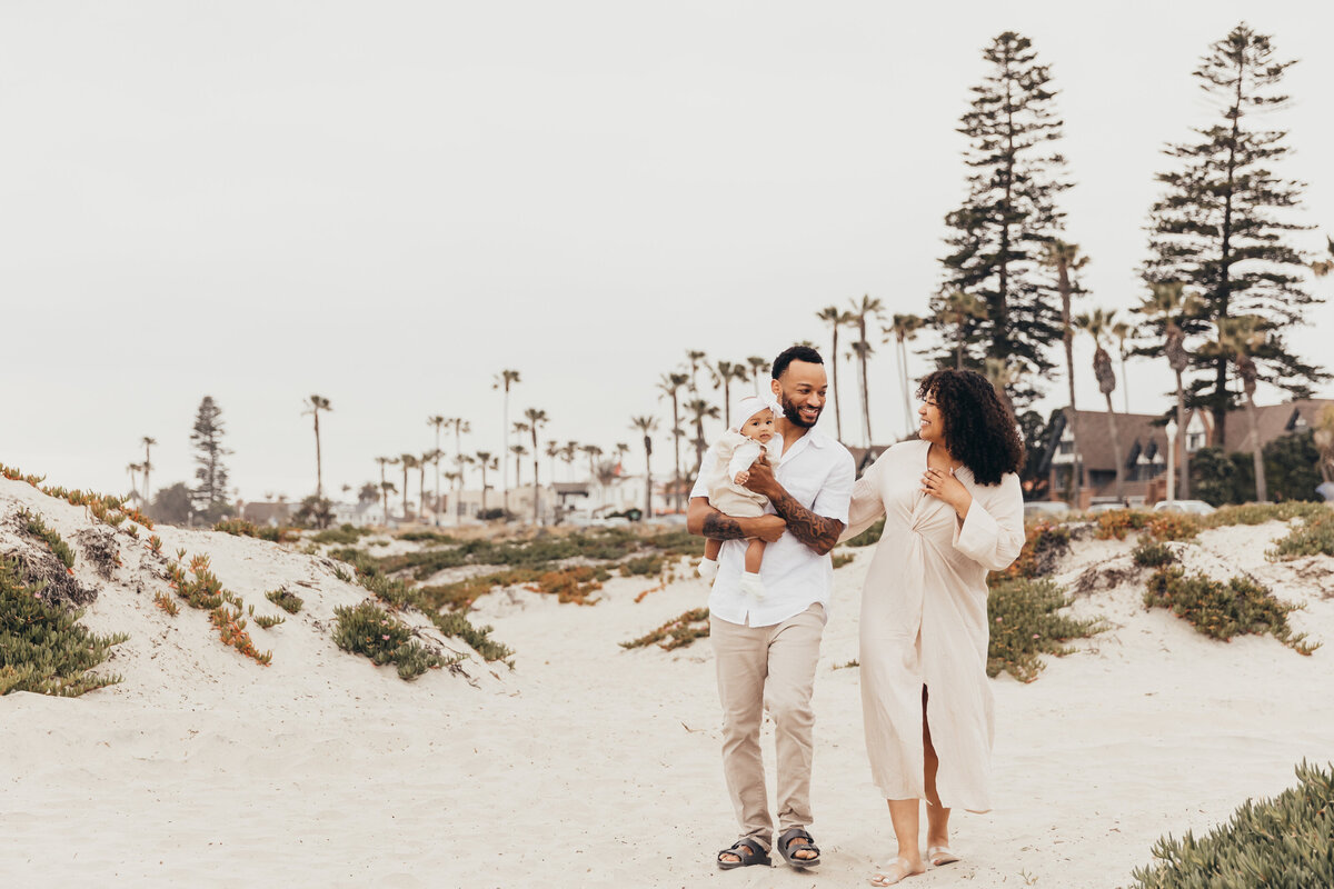 A family of three walk on the gorgeous beach together near Hotel Del Coronado in San Diego