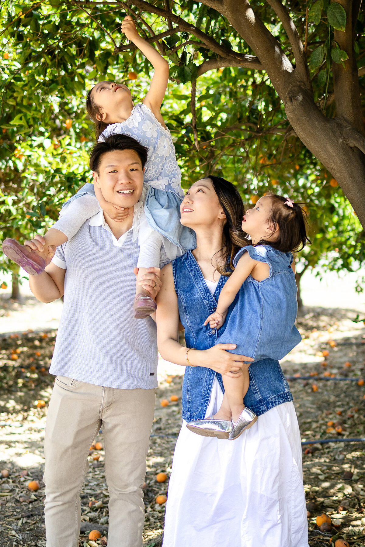 Mom and Dad sharing a warm hug with her two daughters children during a playful outdoor session – lifestyle family photography by Ellobelle Photography, San Francisco Peninsula