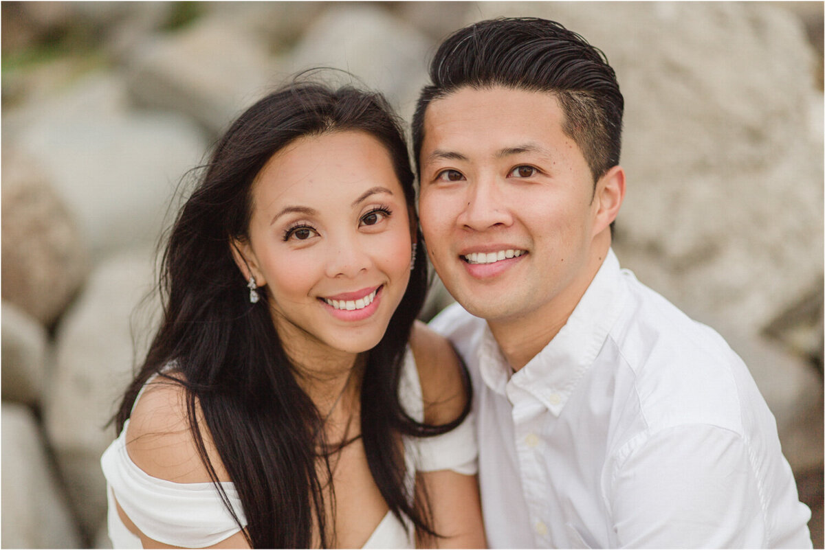 couple in white smiling at camera on beach