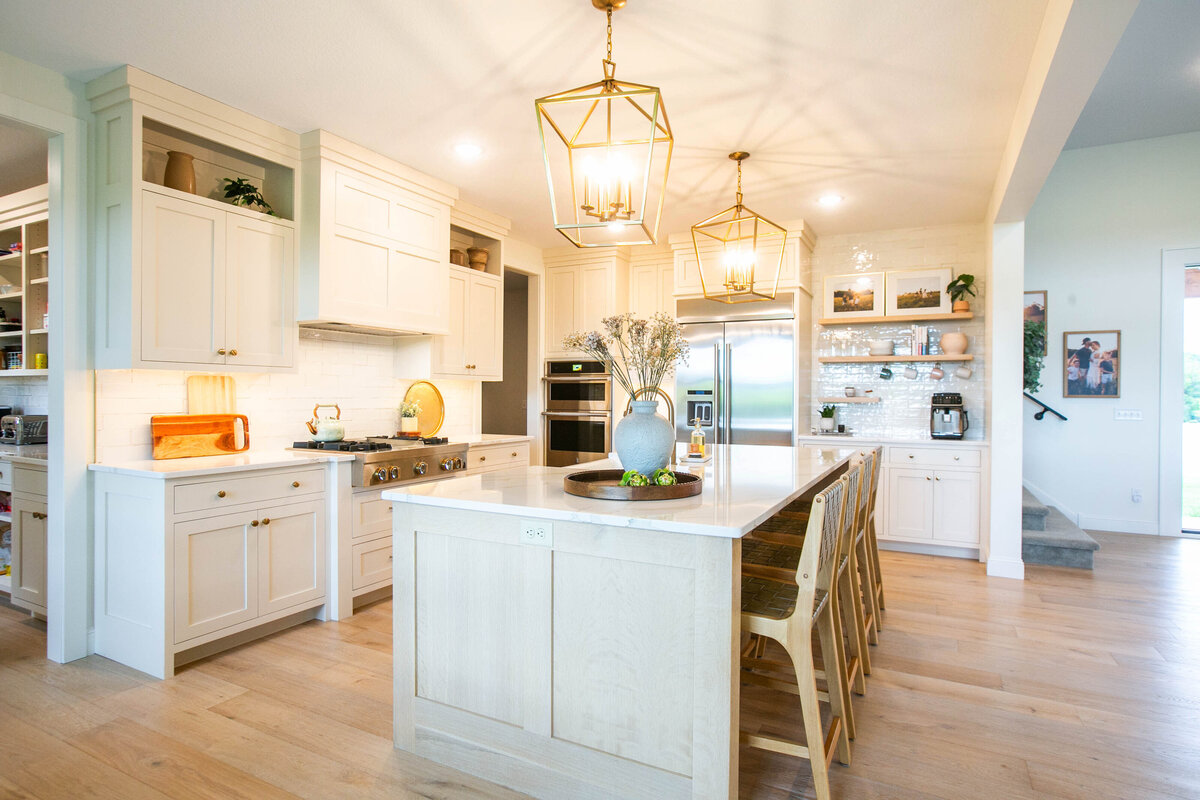 Open kitchen with white cabinets, large island, and quartz countertops in an Otsego custom home