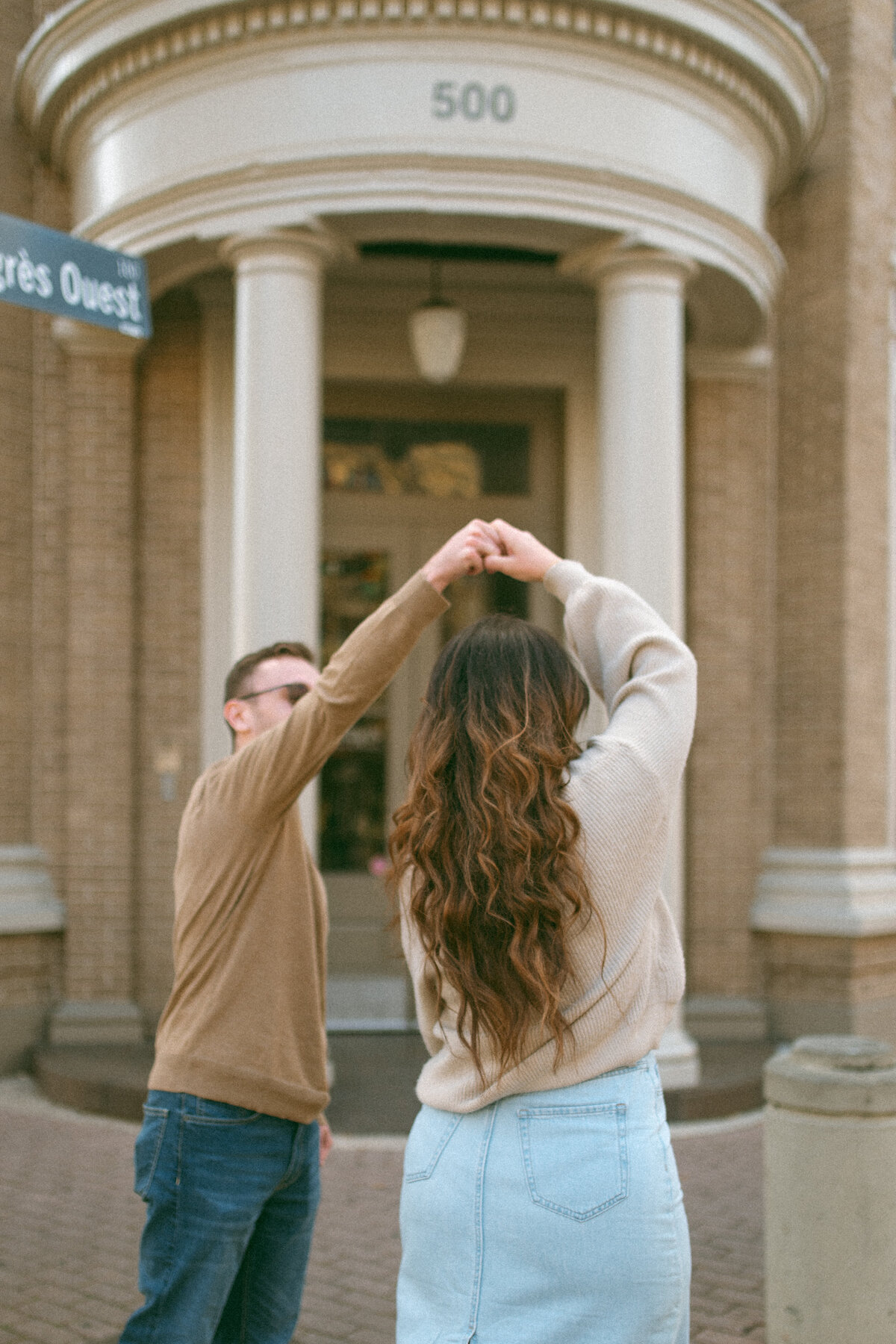 a couple twirling each other in front of a building in downtown lafayette.