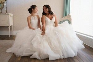 Two brides in elegant white wedding gowns sitting together during bridal photoshoot by St Augustine wedding photographer