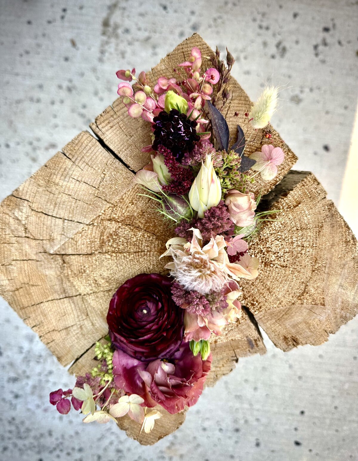 Floral Bridal Crown with burgundy ranunculus, blush lisianthus, scabiosa, hydrangea, and textural accents styled on rustic wood. Designed by Indigo & Violet Co., Bozeman wedding florist.