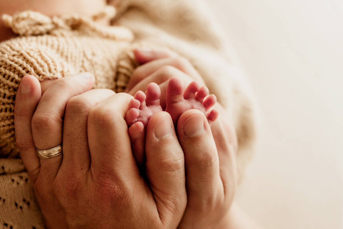 Father places his son's feet in his hands for a close up photo.