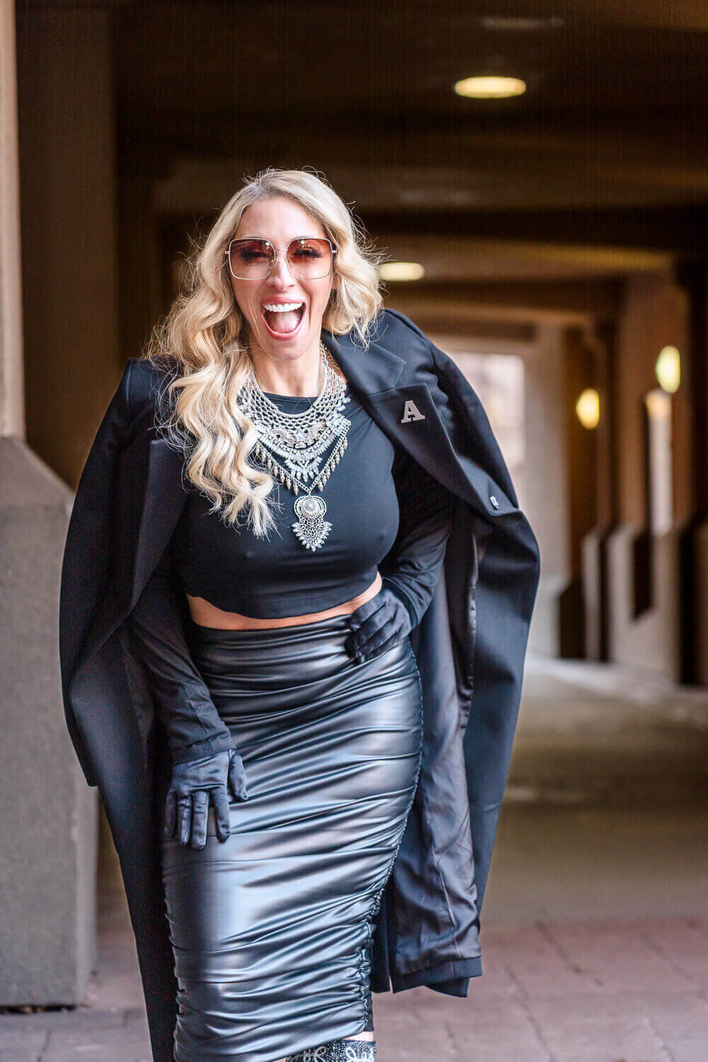 Kelowna photographer capturing businesswoman in black leather skirt and statement necklace during brand photoshoot.