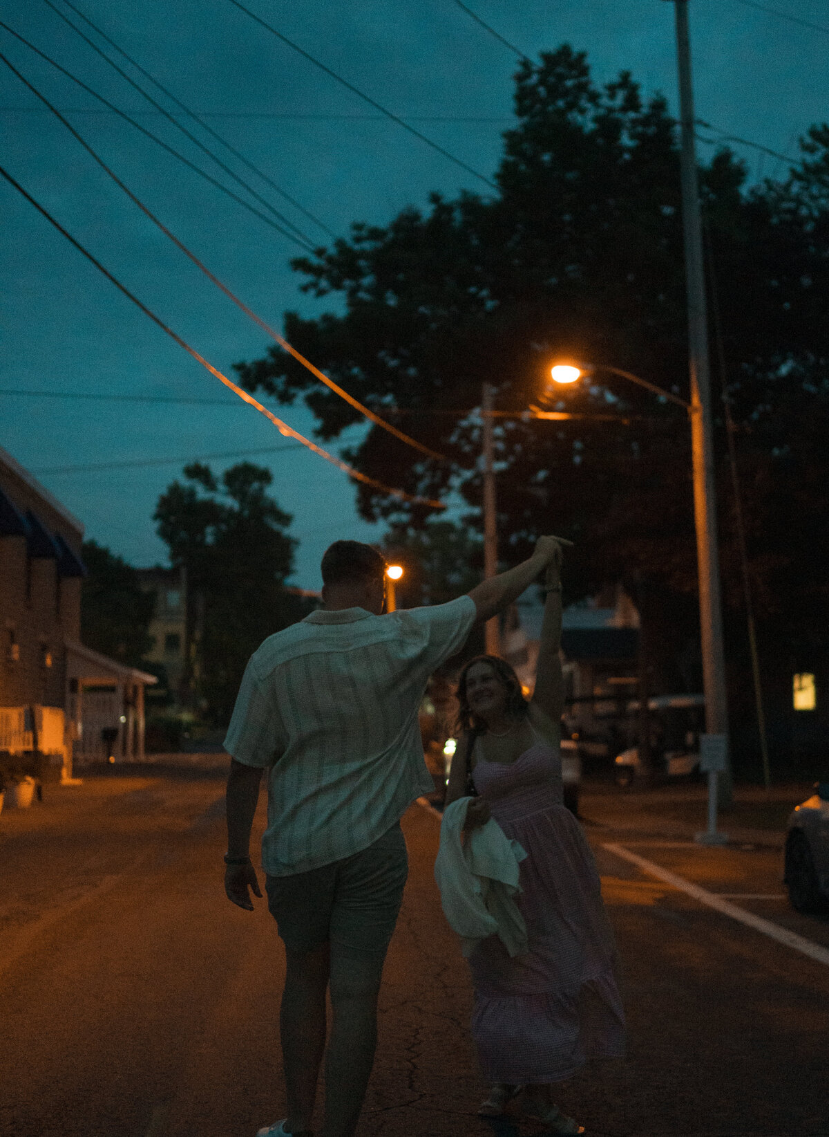 Couples engagement photos in Lakeside Ohio, they are running through the street after dark. Captured in a documentary style.