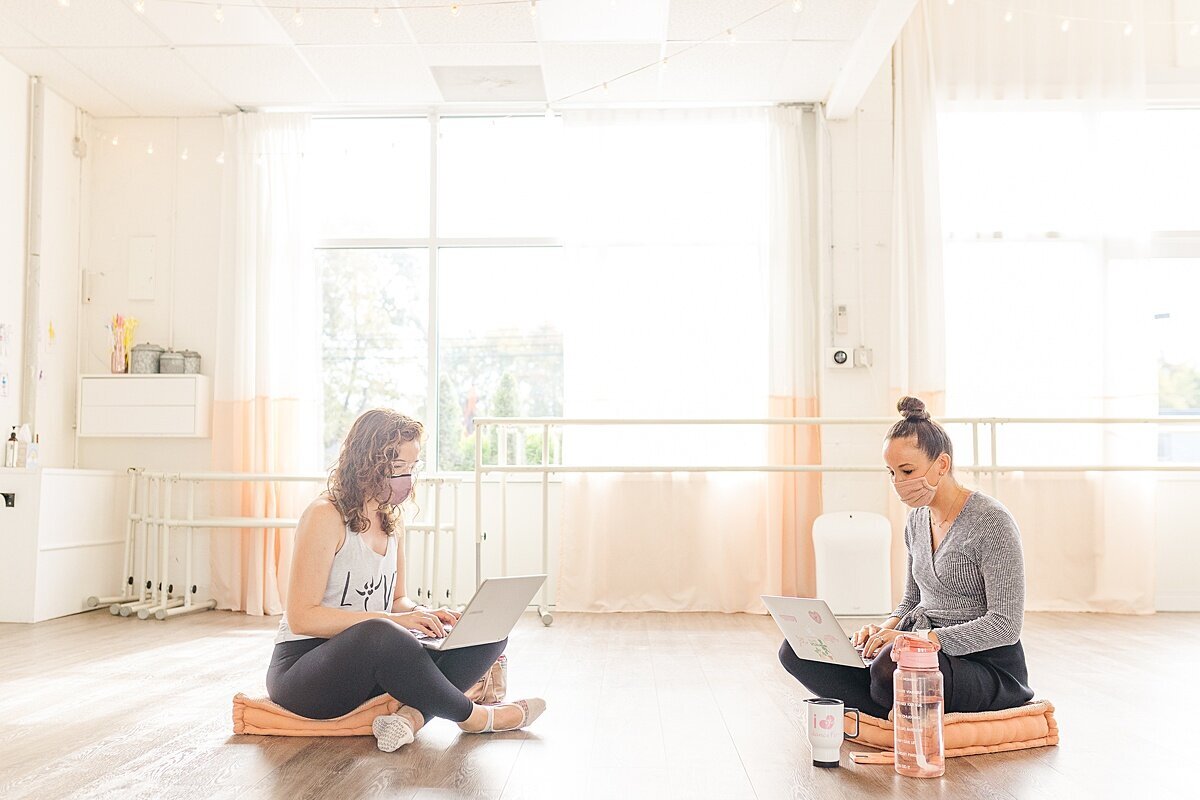 woman sit on computers next to eachotehr during DanceFit Branding photo session with Sara Sniderman Photography in Natick Massachusetts