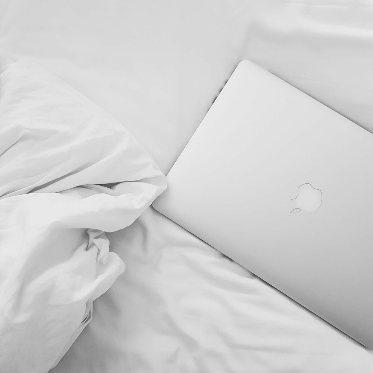 Closed laptop on white bedding, symbolizing work-life balance and building HoneyBook systems that support rest and recovery.