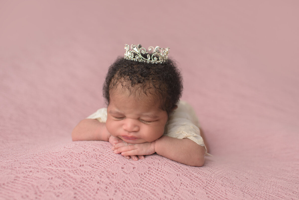baby with a crown and a light pink background