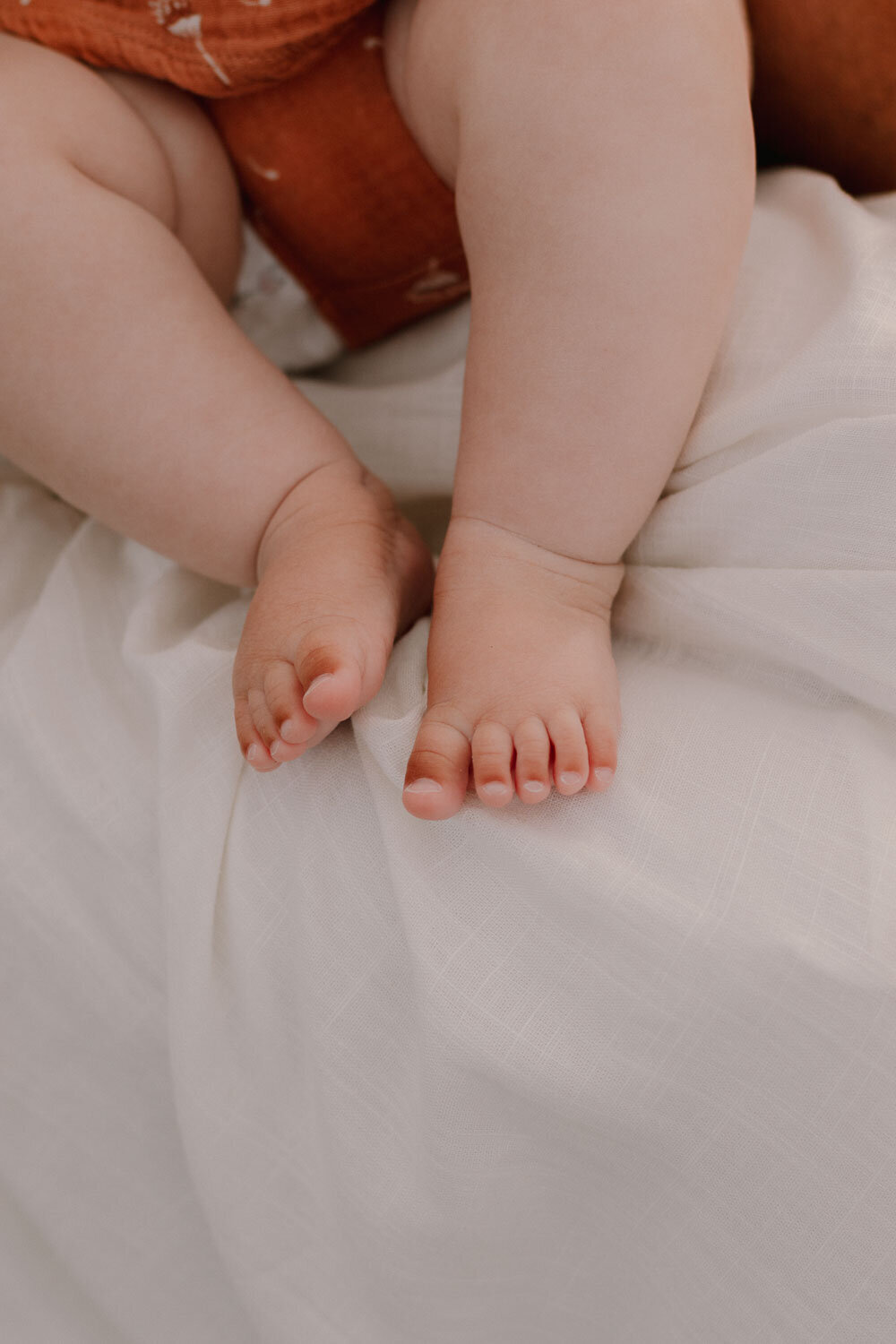 Close-up of baby's feet resting on a white fabric