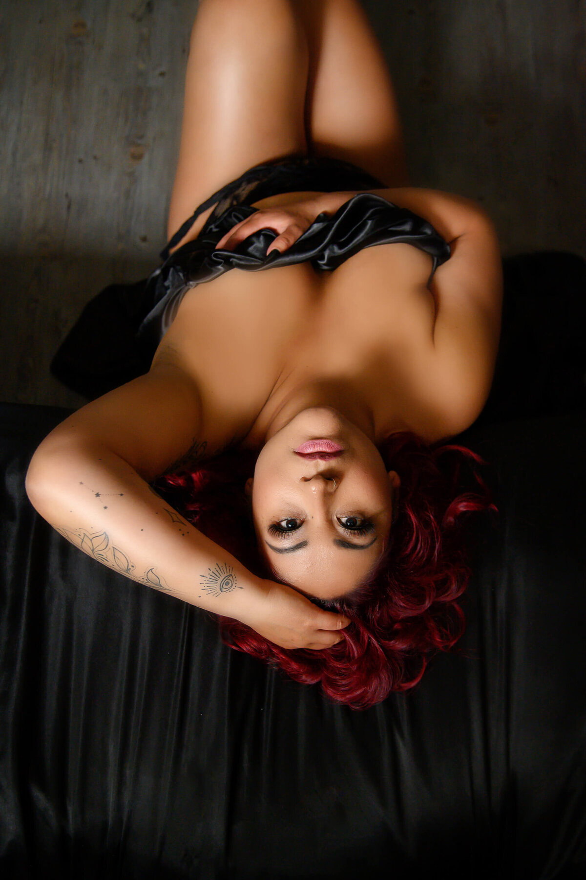 red haired woman sitting on the floor looking up at the camera for her Toronto boudoir photos.