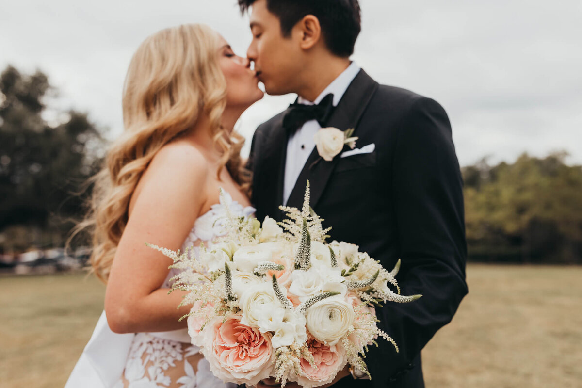 bride holds her bouquet while groom kisses his soon to be wife.