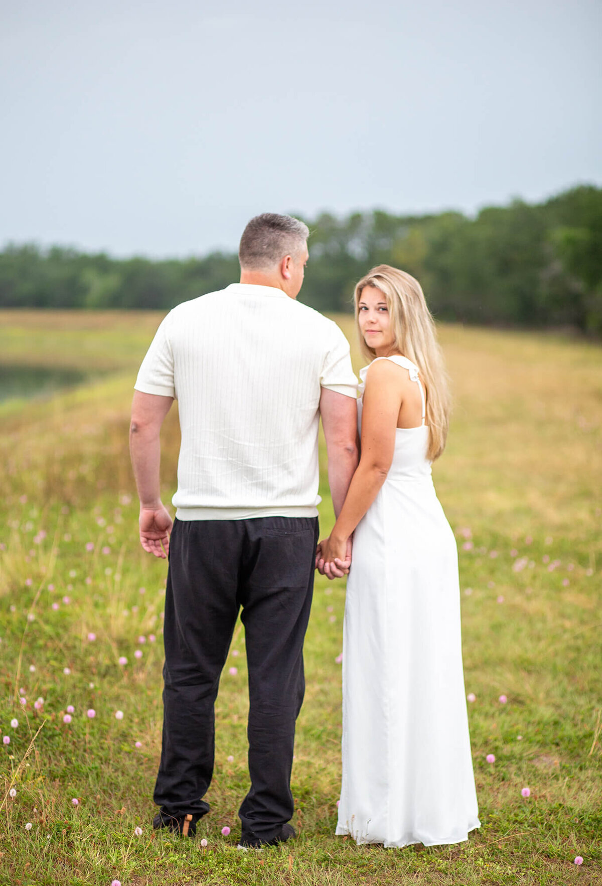 Blonde woman looks over shoulder as her and man walk away through field at Jefferson Equestrian Park, Tampa, FL 