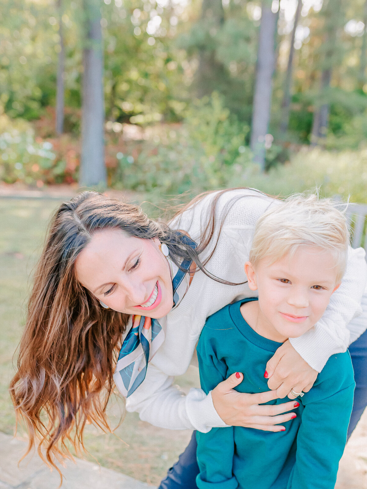 A mother and son share a playful, joyful moment outdoors