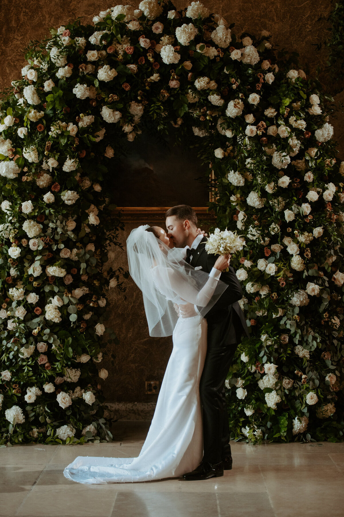 Stunning ceremony floral arch or white roses by Calyx Floral Design, an innovative Red Deer, Alberta wedding florist, featured on the Brontë Bride Vendor Guide.