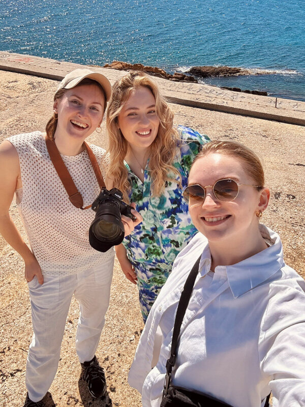 A female photographer, plussize model and hair and make-up artist are taking a selfie on the beach after a photoshoot