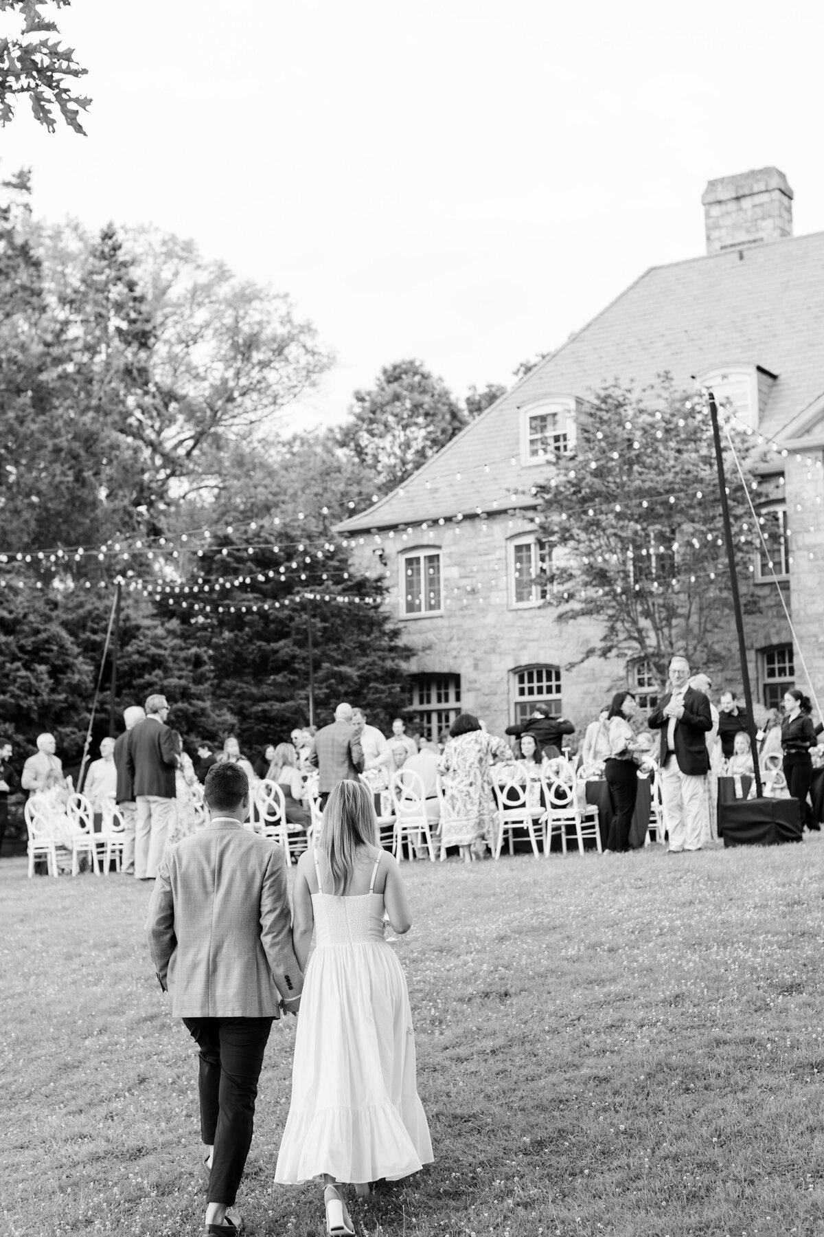 couple holding hand and walking up the lawn to the rehearsal dinner at Wainwright House in Rye