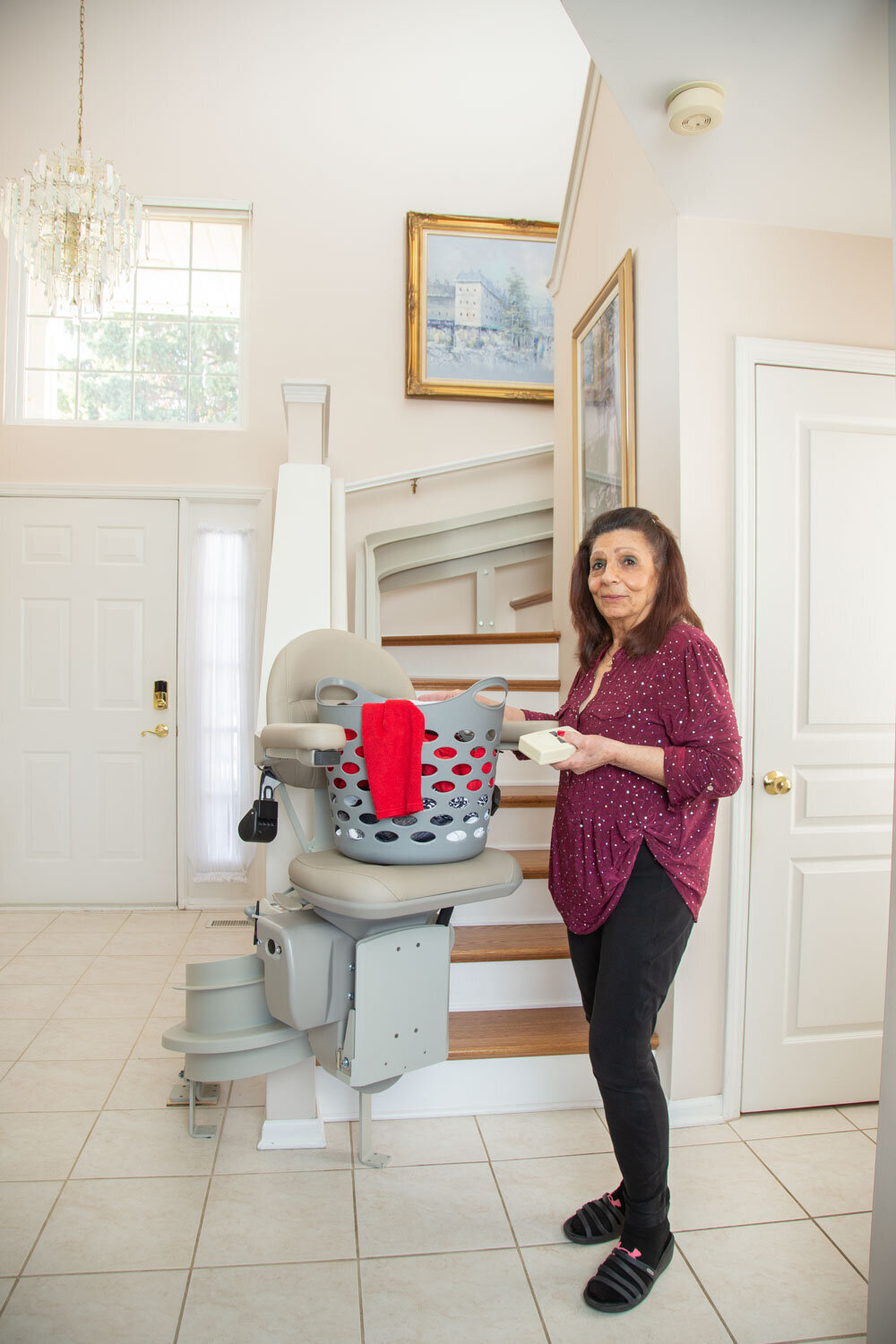 A woman is standing next to a stair lift with a basket on it