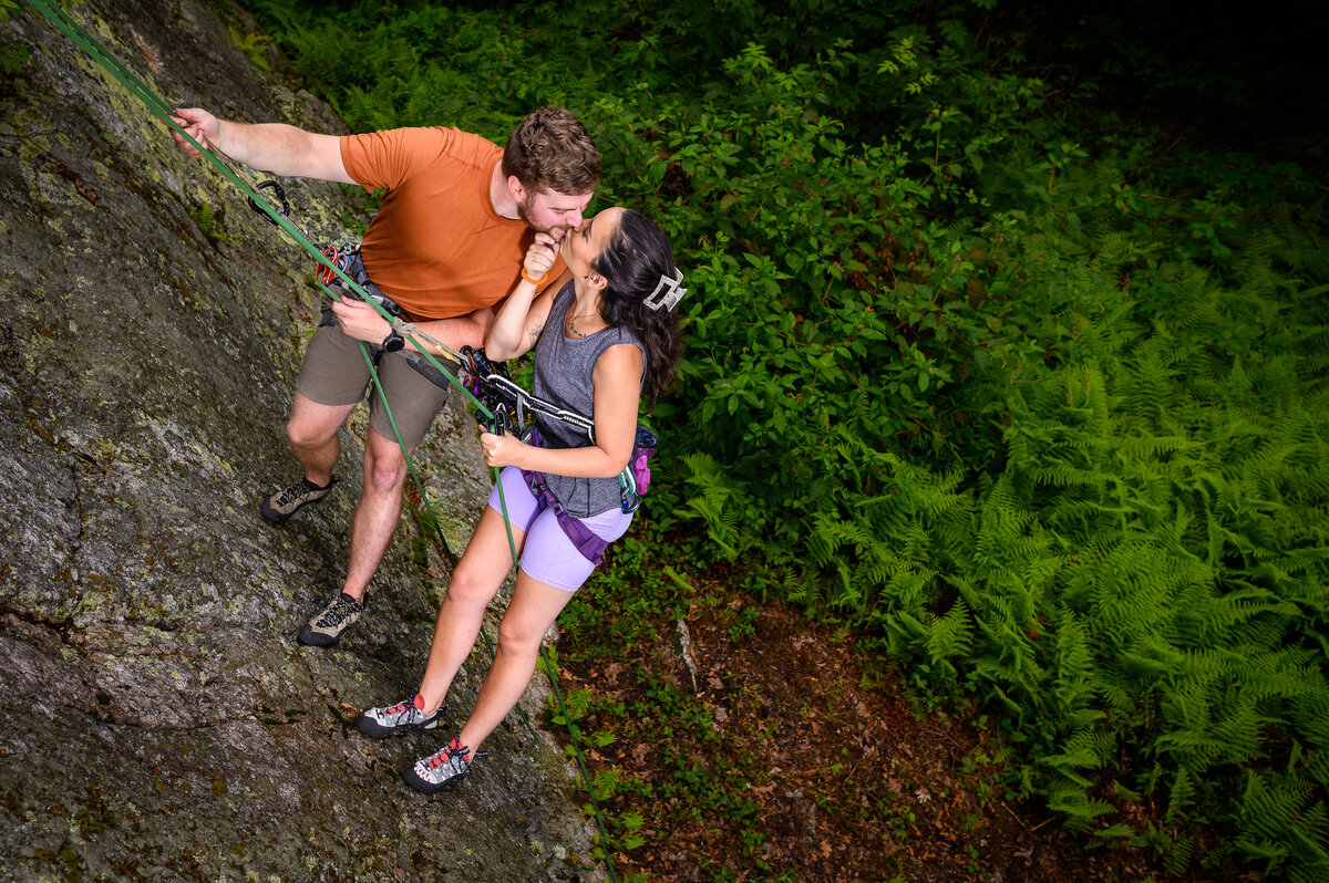 A couple kisses as they rock climb together