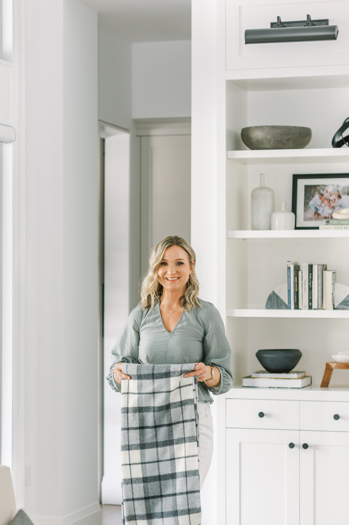 Best Sarnia, ON Interior Designer, Jen Sottosanti is captured folding a blanket in her living room in Sarnia, ON.