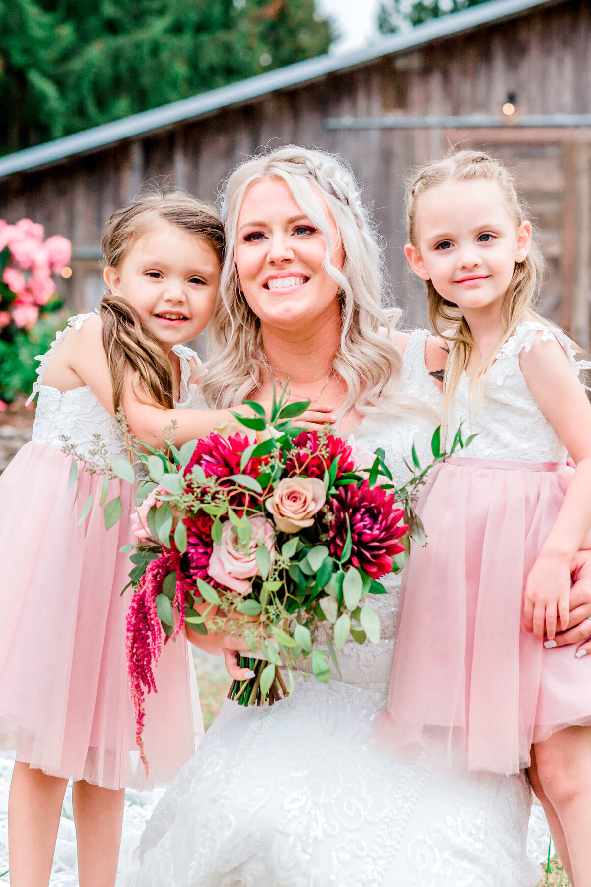 Bride posing with  flower girls in blush pink dresses.