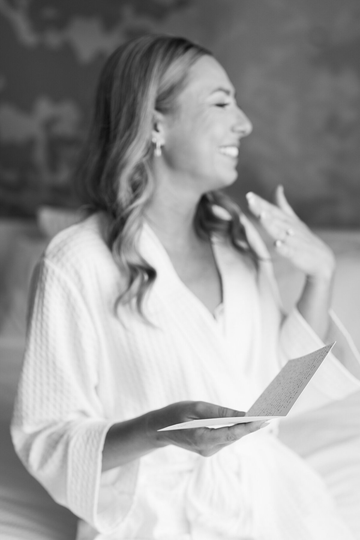 black and white wedding photo of bride reading a note the morning of her wedding as she gets ready